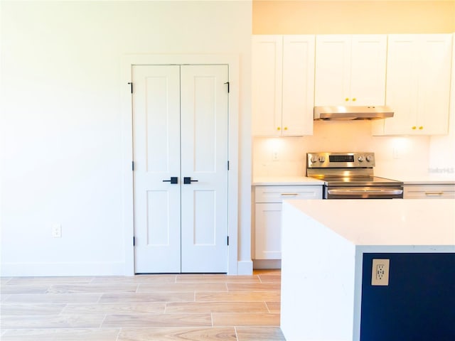 14073 Naylor Ave, Port Charlotte, FL 33981 - kitchen with stainless steel electric stove, under cabinet range hood, white cabinetry, light countertops, and wood tiled floors