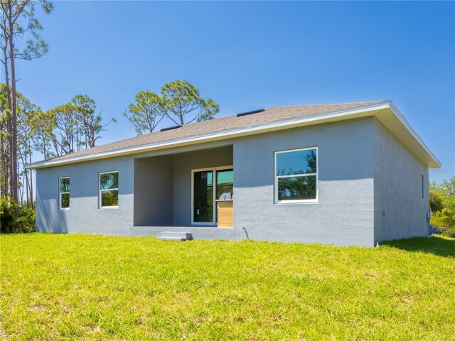 14073 Naylor Ave, Port Charlotte, FL 33981 - back of house with stucco siding and a yard