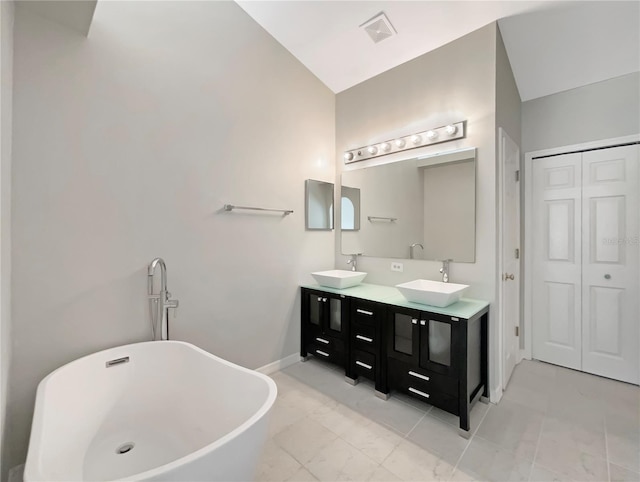 4209 SW 33rd St, Ocala, FL 34474 - bathroom featuring double vanity, a freestanding tub, a closet, marble look tiles, and lofted ceiling
