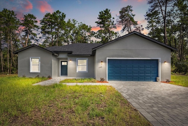 17445 SW 41st Cir, Ocala, FL 34473 - ranch-style home with decorative driveway, an attached garage, stucco siding, a lawn, and a shingled roof