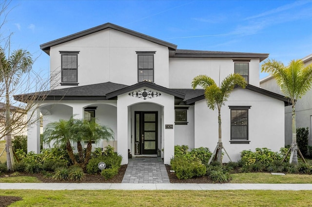 7454 Gathering Dr, Reunion, FL 34747 - view of front of home featuring stucco siding, a shingled roof, a front lawn, and covered porch