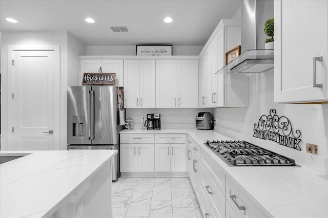7454 Gathering Dr, Reunion, FL 34747 - kitchen featuring wall chimney range hood, stainless steel appliances, light marble finish floors, white cabinets, and recessed lighting