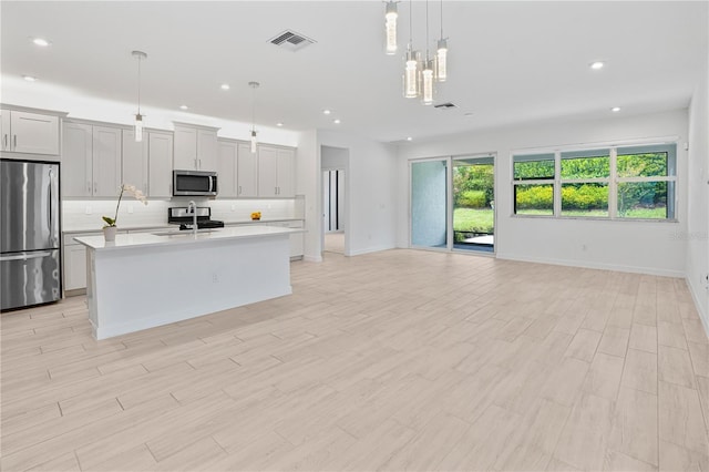 11687 SW Viridian Blvd, Port St Lucie, FL 34987 - kitchen with appliances with stainless steel finishes, open floor plan, a kitchen island with sink, light countertops, and decorative backsplash