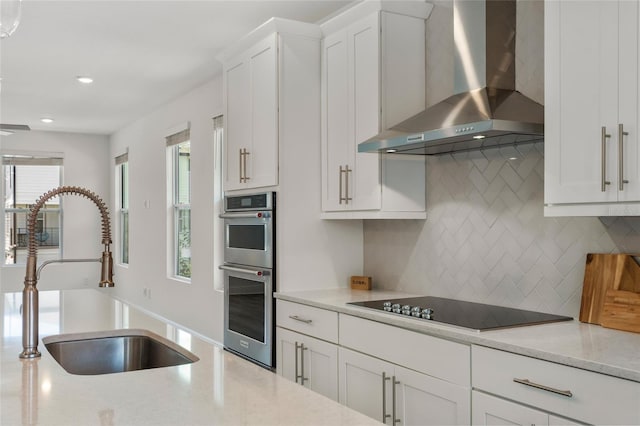 8484 Sperry St, Orlando, FL 32827 - kitchen featuring wall chimney exhaust hood, black electric stovetop, stainless steel double oven, backsplash, and recessed lighting