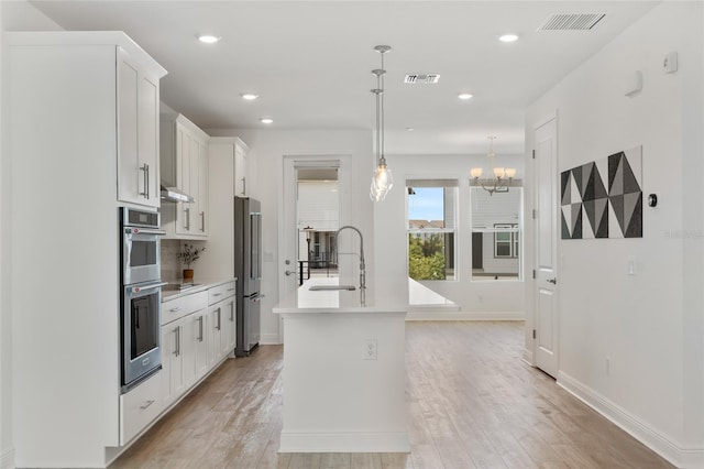 8484 Sperry St, Orlando, FL 32827 - kitchen with appliances with stainless steel finishes, light wood-style flooring, light countertops, white cabinetry, and a chandelier