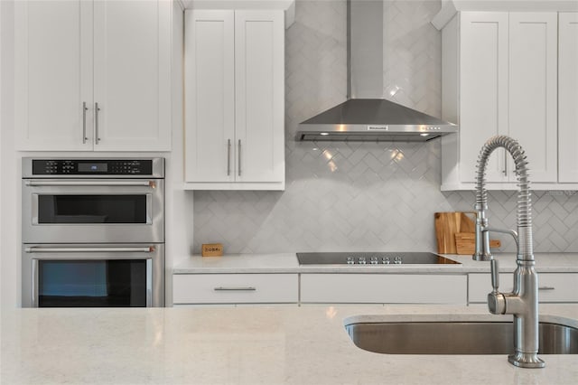 8484 Sperry St, Orlando, FL 32827 - kitchen featuring wall chimney range hood, stainless steel double oven, backsplash, and white cabinets