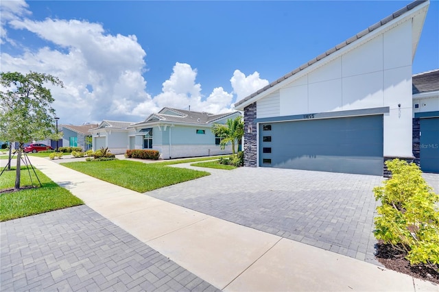 11695 SW Viridian Blvd, Port St Lucie, FL 34987 - view of front of house with decorative driveway, stone siding, a front yard, and a garage
