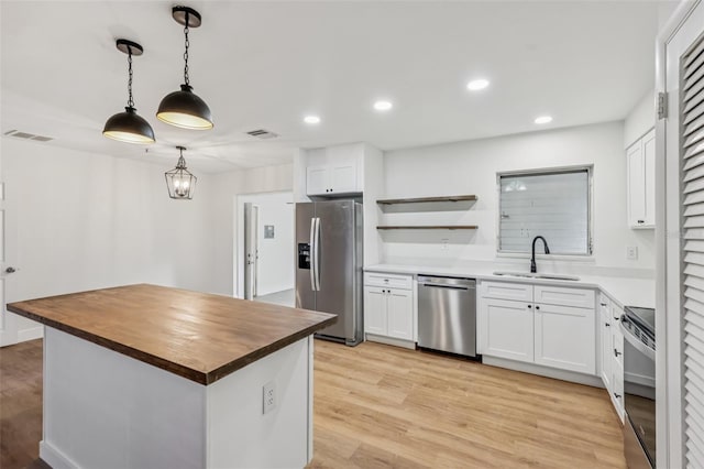 1320 E Lombardy Dr, Deltona, FL 32725 - kitchen featuring appliances with stainless steel finishes, wood counters, light wood finished floors, white cabinetry, and recessed lighting