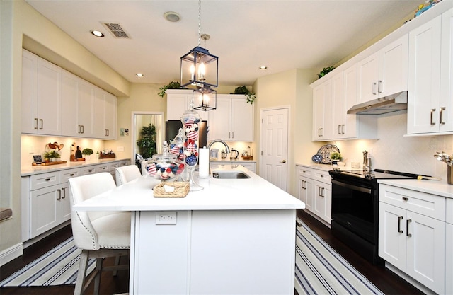 436 Skyview Pl, Chuluota, FL 32766 - kitchen with black electric range oven, under cabinet range hood, light countertops, a breakfast bar area, and white cabinetry
