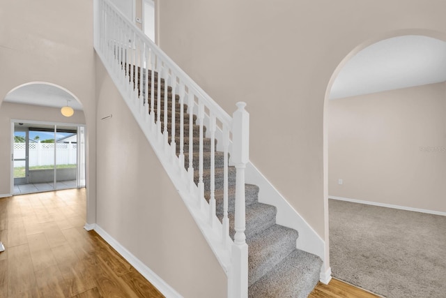 16053 Wilkinson Dr, Clermont, FL 34714 - staircase with arched walkways, wood finished floors, and a towering ceiling