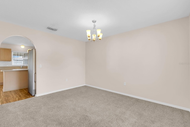 16053 Wilkinson Dr, Clermont, FL 34714 - empty room featuring a chandelier, light colored carpet, and arched walkways
