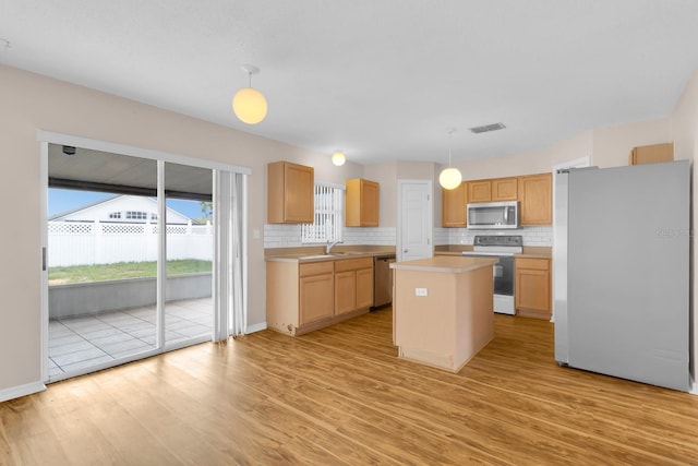 16053 Wilkinson Dr, Clermont, FL 34714 - kitchen featuring appliances with stainless steel finishes, light countertops, light wood-style floors, decorative backsplash, and a center island