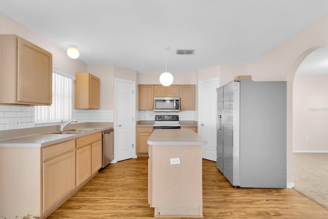 16053 Wilkinson Dr, Clermont, FL 34714 - kitchen featuring stainless steel appliances, light brown cabinetry, a kitchen island, arched walkways, and light countertops