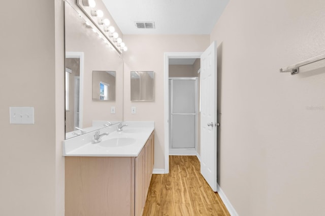16053 Wilkinson Dr, Clermont, FL 34714 - bathroom featuring double vanity, wood finished floors, and a shower with door