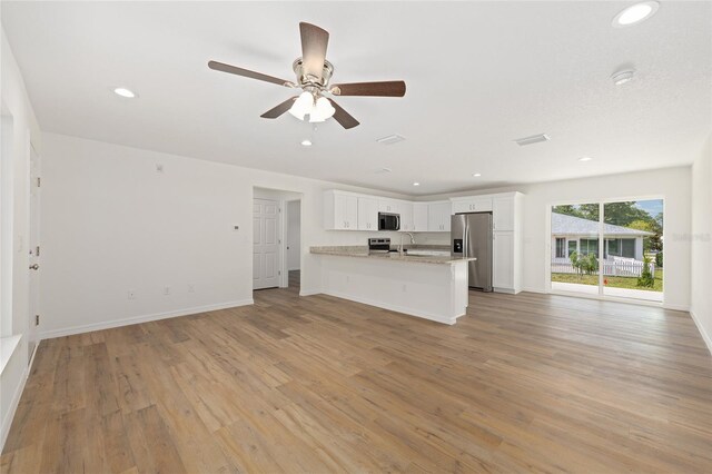13031 NE 7th Loop, Silver Springs, FL 34488 - kitchen with stainless steel appliances, open floor plan, white cabinetry, light wood-style flooring, and recessed lighting