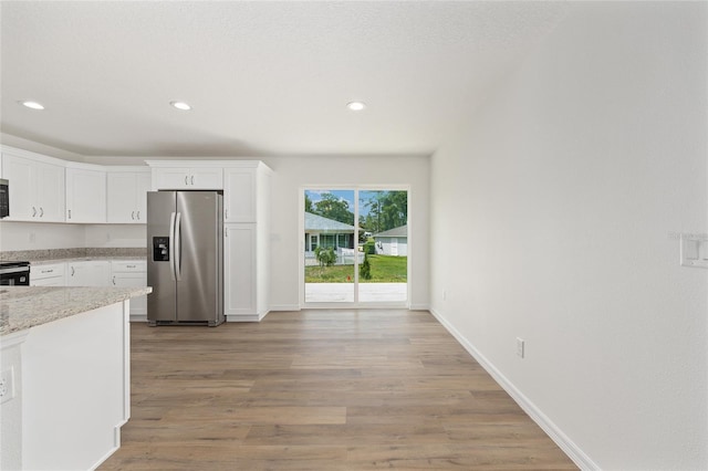 13031 NE 7th Loop, Silver Springs, FL 34488 - kitchen with appliances with stainless steel finishes, white cabinets, recessed lighting, light wood-style flooring, and light stone countertops