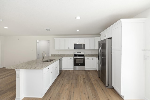 13031 NE 7th Loop, Silver Springs, FL 34488 - kitchen featuring stainless steel appliances, a peninsula, light wood finished floors, white cabinetry, and light stone counters