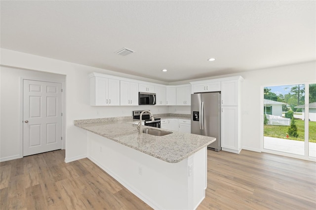 13031 NE 7th Loop, Silver Springs, FL 34488 - kitchen with appliances with stainless steel finishes, light wood-style flooring, a peninsula, white cabinetry, and recessed lighting