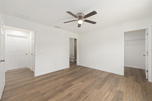 13031 NE 7th Loop, Silver Springs, FL 34488 - unfurnished bedroom featuring a walk in closet, wood finished floors, a closet, and a ceiling fan