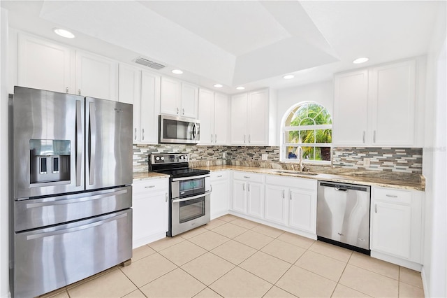 9003 Pecky Cypress Way, Orlando, FL 32836 - kitchen featuring appliances with stainless steel finishes, white cabinets, decorative backsplash, light stone countertops, and recessed lighting