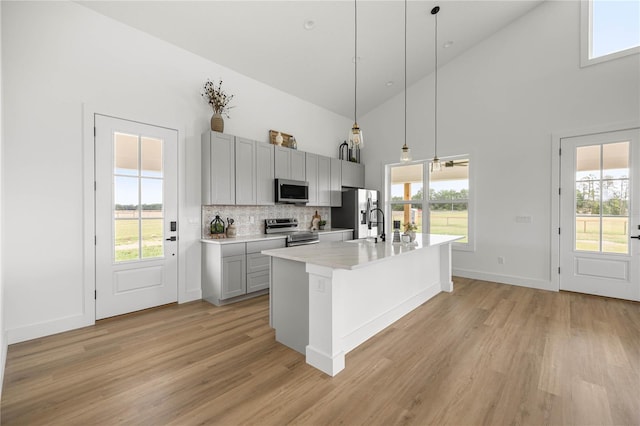 2212 SW 210th Ave, Dunnellon, FL 34431 - kitchen with appliances with stainless steel finishes, high vaulted ceiling, light wood finished floors, light countertops, and a kitchen island with sink