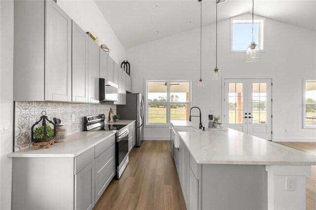 2212 SW 210th Ave, Dunnellon, FL 34431 - kitchen with appliances with stainless steel finishes, an island with sink, light wood-style flooring, high vaulted ceiling, and decorative backsplash