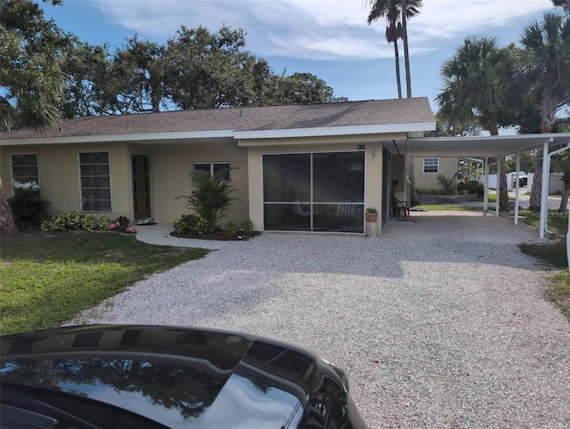417 Shore Rd, Nokomis, FL 34275 - view of front of home with stucco siding, gravel driveway, an attached carport, and a front lawn