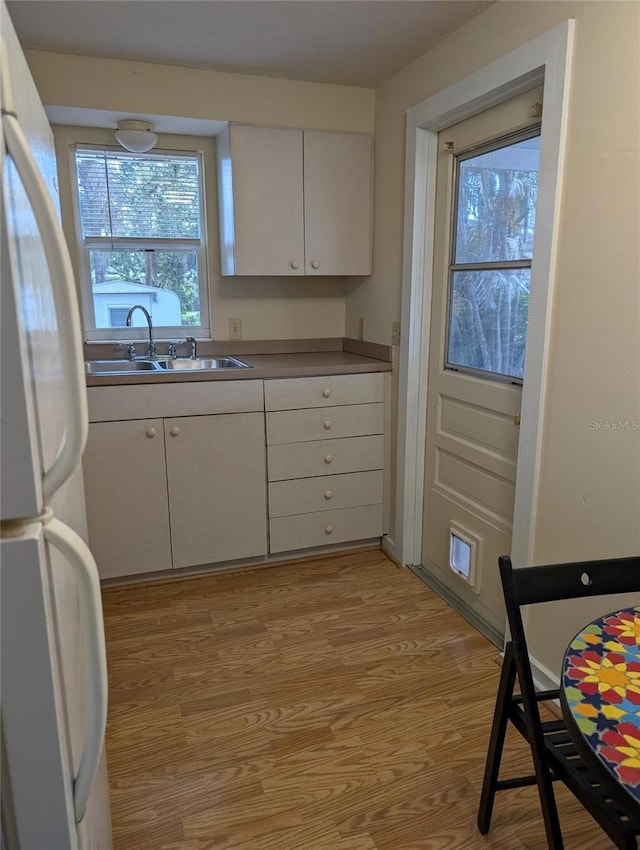 417 Shore Rd, Nokomis, FL 34275 - kitchen featuring freestanding refrigerator, light wood-style flooring, and white cabinetry