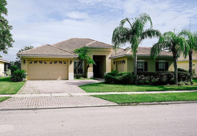 3504 Shorewood Dr, Kissimmee, FL 34746 - mediterranean / spanish-style house with stucco siding, a garage, decorative driveway, a front lawn, and a tiled roof