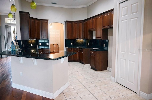 3504 Shorewood Dr, Kissimmee, FL 34746 - kitchen featuring a peninsula, dark countertops, arched walkways, tasteful backsplash, and ornamental molding