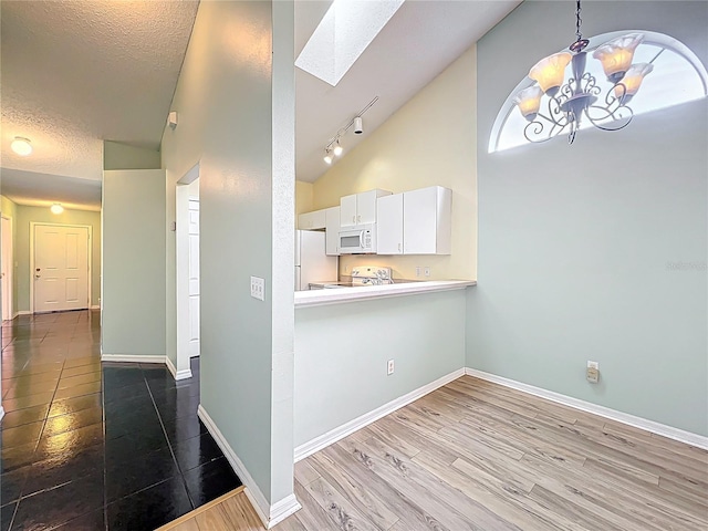1751 Chatham Cir, Apopka, FL 32703 - kitchen featuring white appliances, a skylight, a chandelier, white cabinets, and high vaulted ceiling