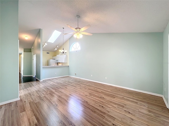 1751 Chatham Cir, Apopka, FL 32703 - unfurnished living room featuring ceiling fan, wood finished floors, a skylight, a textured ceiling, and vaulted ceiling