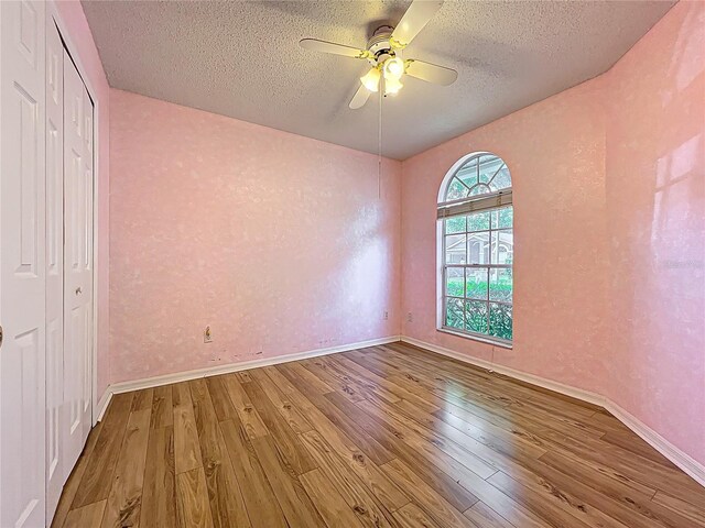 1751 Chatham Cir, Apopka, FL 32703 - unfurnished bedroom with wood finished floors, a textured ceiling, ceiling fan, a closet, and a textured wall