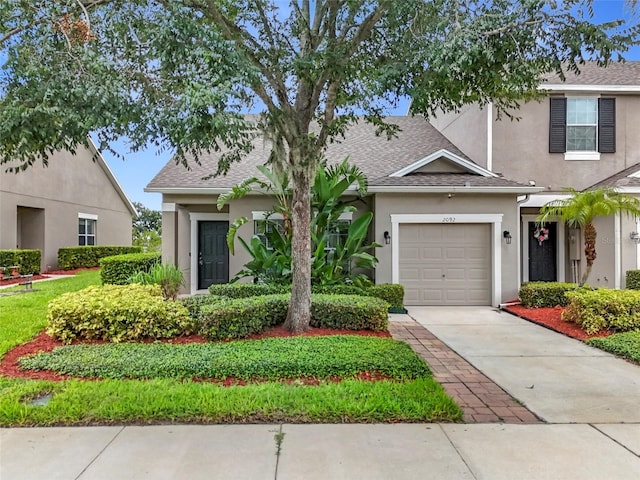 2092 Switch Grass Cir, Ocoee, FL 34761 - view of front of home featuring stucco siding, driveway, a shingled roof, and a garage