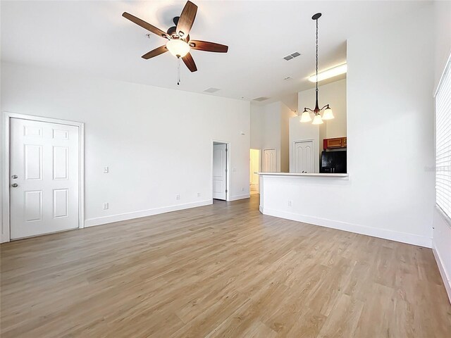 2092 Switch Grass Cir, Ocoee, FL 34761 - unfurnished living room with a towering ceiling, ceiling fan, light wood finished floors, and a chandelier