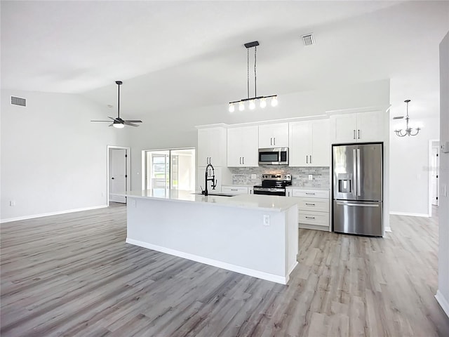 142 Broadmoor Ln, Rotonda West, FL 33947 - kitchen featuring stainless steel appliances, light wood finished floors, a ceiling fan, vaulted ceiling, and white cabinetry