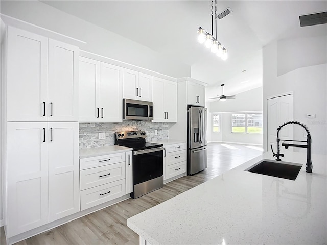 142 Broadmoor Ln, Rotonda West, FL 33947 - kitchen with stainless steel appliances, backsplash, ceiling fan, light wood-type flooring, and vaulted ceiling