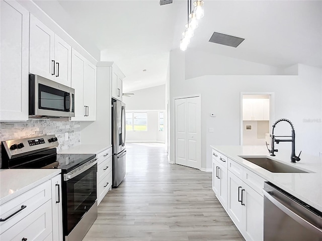 142 Broadmoor Ln, Rotonda West, FL 33947 - kitchen with appliances with stainless steel finishes, lofted ceiling, decorative backsplash, light countertops, and light wood finished floors
