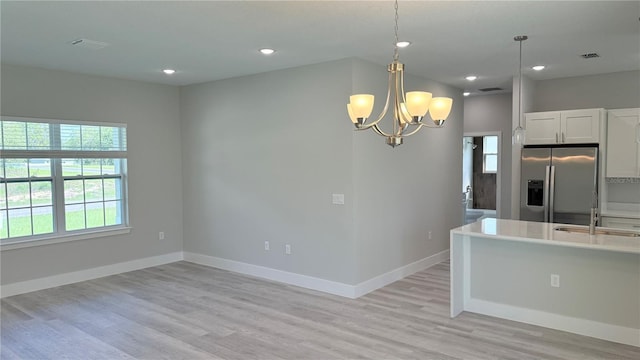 2451 W Menores Dr, Citrus Springs, FL 34434 - kitchen featuring stainless steel fridge with ice dispenser, a chandelier, light wood-style flooring, white cabinetry, and pendant lighting