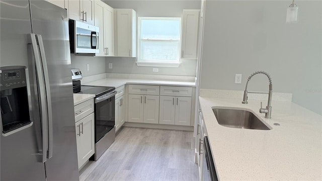 2451 W Menores Dr, Citrus Springs, FL 34434 - kitchen with appliances with stainless steel finishes, light wood-type flooring, light stone counters, pendant lighting, and white cabinetry