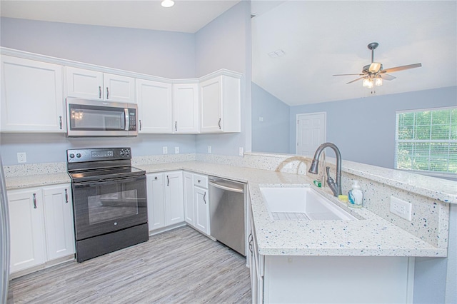 4911 NE 7th St, Ocala, FL 34470 - kitchen featuring appliances with stainless steel finishes, a peninsula, lofted ceiling, light wood-type flooring, and white cabinets