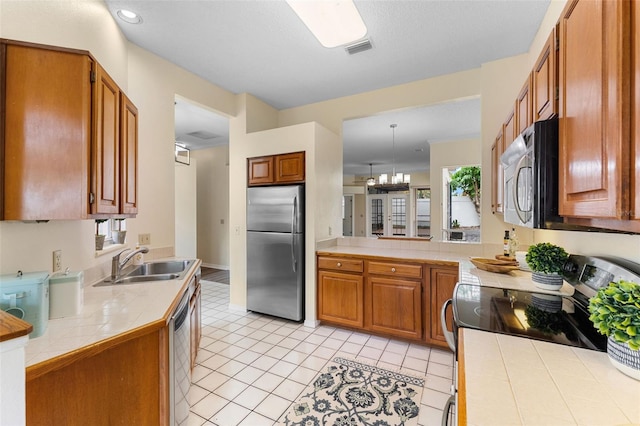 14558 Mandolin Dr, Orlando, FL 32837 - kitchen featuring stainless steel appliances, brown cabinets, tile counters, light tile patterned floors, and recessed lighting