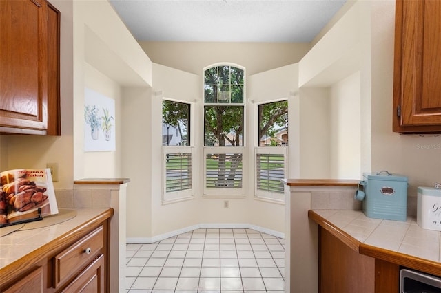 14558 Mandolin Dr, Orlando, FL 32837 - kitchen with tile counters, brown cabinets, and light tile patterned floors