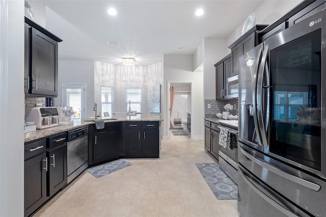 28 Noah Blvd, Flagler Beach, FL 32136 - kitchen featuring stainless steel appliances, decorative backsplash, a peninsula, light stone counters, and recessed lighting