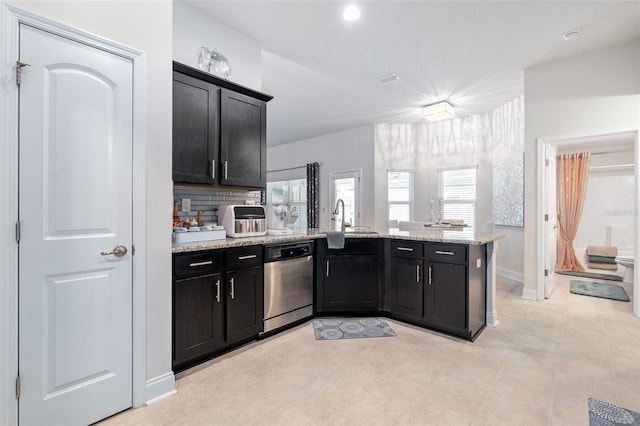 28 Noah Blvd, Flagler Beach, FL 32136 - kitchen featuring dishwasher, a peninsula, dark cabinetry, light stone countertops, and tasteful backsplash