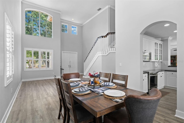 12978 SW 26th St, Miramar, FL 33027 - dining room with wood finished floors, stairway, crown molding, arched walkways, and a towering ceiling