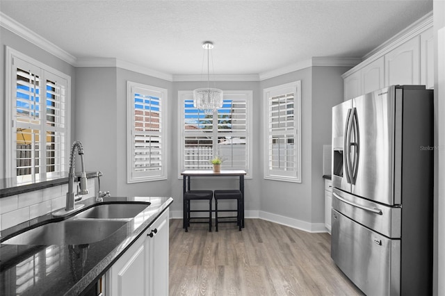 12978 SW 26th St, Miramar, FL 33027 - kitchen featuring stainless steel fridge with ice dispenser, light wood-style floors, plenty of natural light, white cabinetry, and a textured ceiling