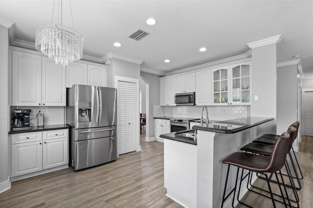 12978 SW 26th St, Miramar, FL 33027 - kitchen featuring appliances with stainless steel finishes, crown molding, arched walkways, dark countertops, and glass insert cabinets
