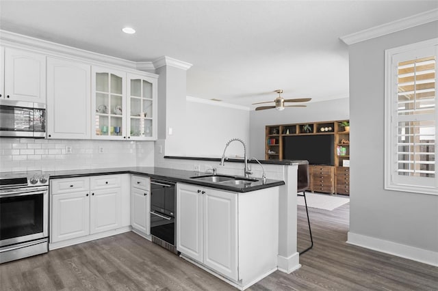 12978 SW 26th St, Miramar, FL 33027 - kitchen with appliances with stainless steel finishes, a peninsula, crown molding, dark wood-style flooring, and dark countertops