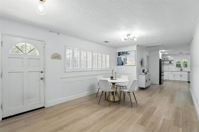 4611 Cranston Pl, Orlando, FL 32812 - dining space with a chandelier, light wood-style flooring, a textured ceiling, and ornamental molding